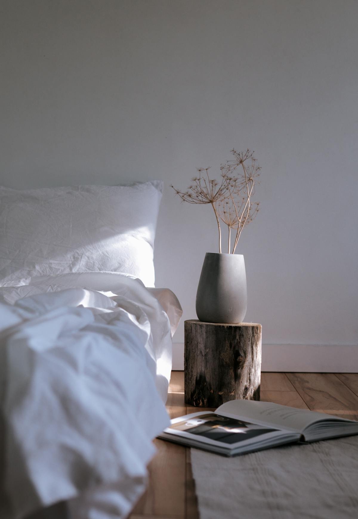 Quarto estilo wabi-sabi com roupa de cama em linho, vaso de cerâmica e tronco de madeira natural